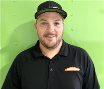 SERVPRO employee in front of green back background.